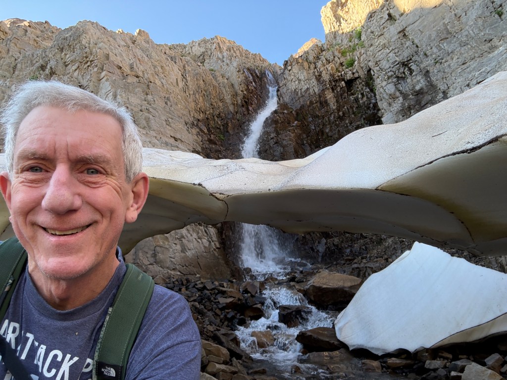Old Hiking Dude by snow bridge and waterfall