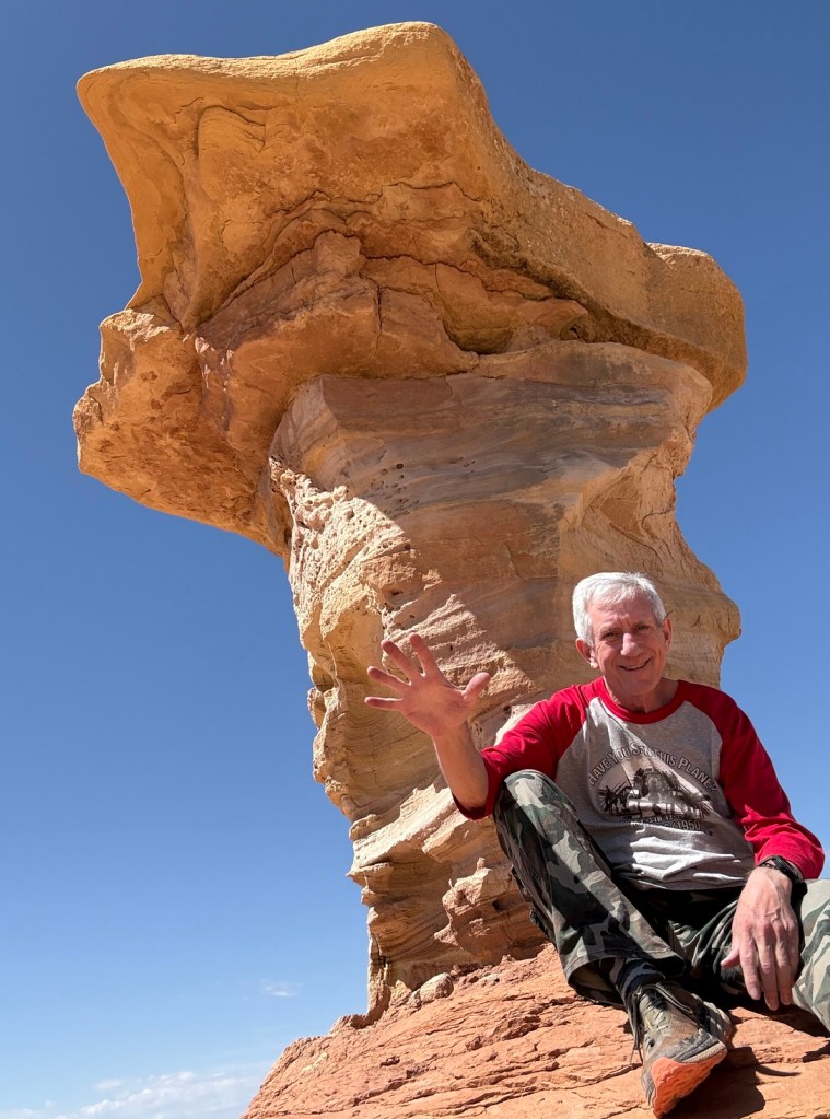 Old Hiking Dude relaxing by a mushroom rock near Little Wild Horse Canyon Utah